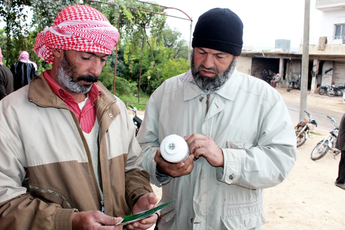 Farmers comparing fertilizers and seeds bought with their vouchers, outside a small agricultural supply shop in northern Idlib.